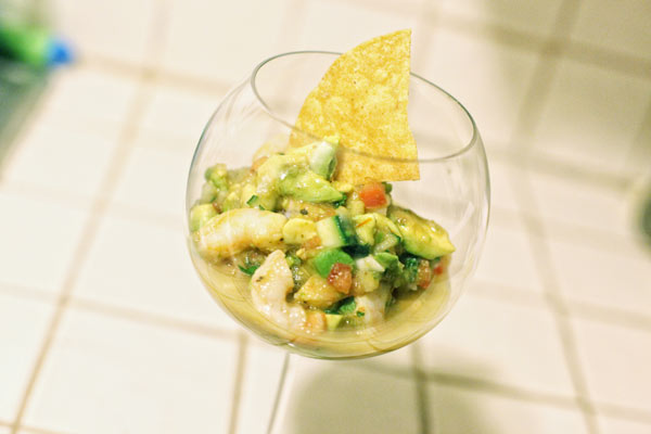 Shrimp cocktail with a corn chip in a pretty glass.